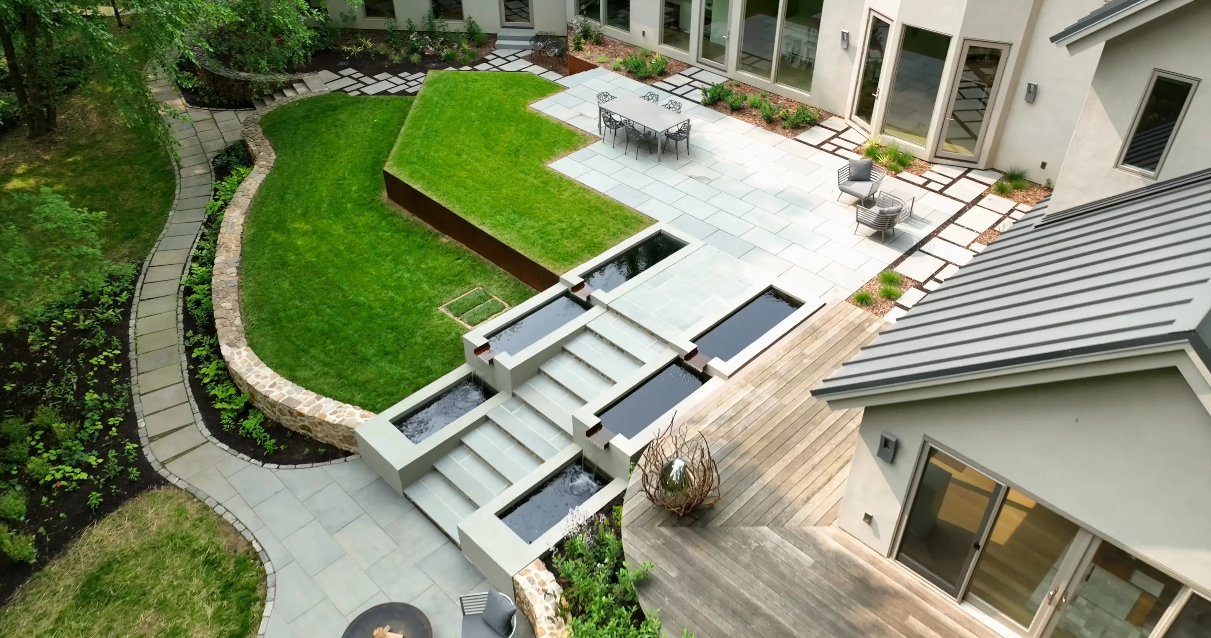 Expansive landscape project featuring stonework, native plantings, and a cascading water feature